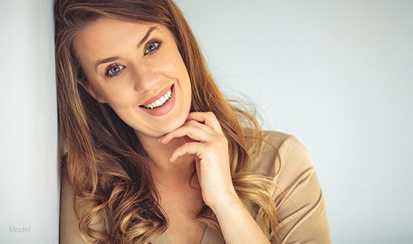Female model smiling brightly with her hand up to her chin