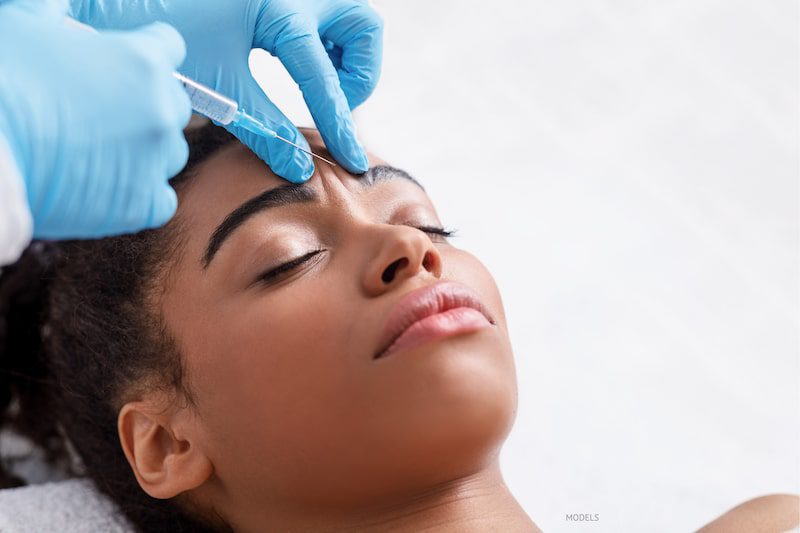 Young black woman getting BOTOX® Cosmetic injected in her frown lines.