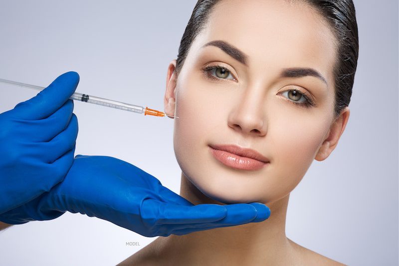 woman gets filler injection into cheeks by doctor