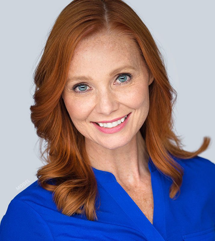 Professional headshot of a redheaded woman in a blue blouse