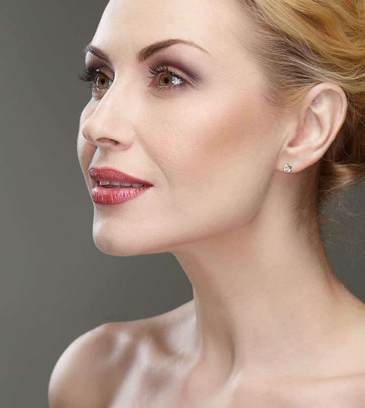 Close up headhshot of a woman with bare shoulders and earrings