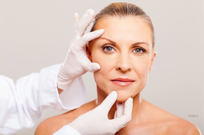 Middle aged woman getting examined for a facial treatment.