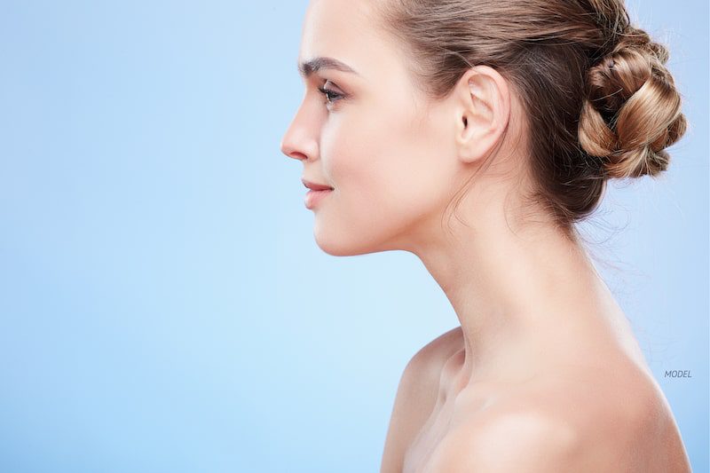 Profile of young woman's face against a blue backdrop.