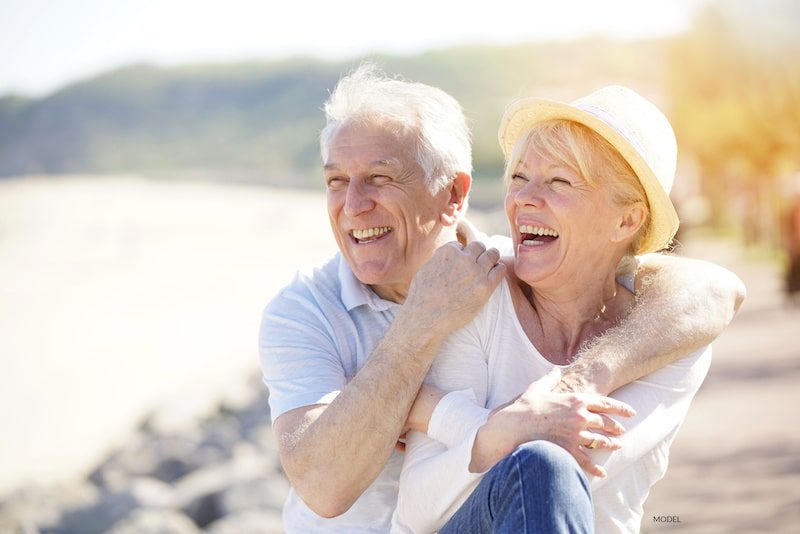 Happy older couple sitting outside by the coast.